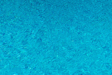 Fototapeta na wymiar Blue water in swimming pool background. Ripple Water in swimming pool with sun reflection. Blue swimming pool rippled water detail