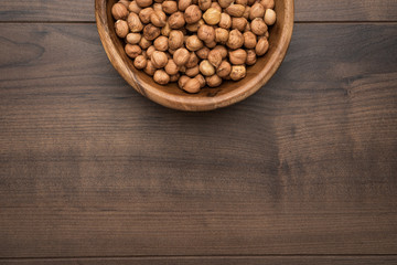 photo of a bowl full of hazelnuts on the brown wooden table with copy space