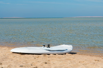 windsurf board on a golden beach. The concept of a beach holiday and a healthy lifestyle