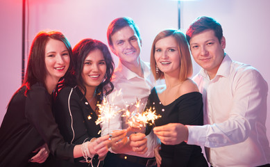 New year party, celebration and holidays concept - group of friends having fun with sparklers