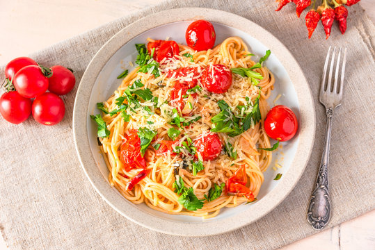 Pasta al pomodoro - spaghetti with cherry tomatoes on a plate close-up in a rustic style, top view