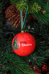 Christmas tree hanging ornament, red globe with write merry christmas, close up