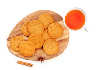 A photo of ginger cookies with a cup of tea, a cinnamon stick, and an anise star, shot from the top on a white background with a place for text