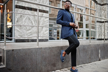 Amazingly looking african american man wear at blue blazer with brooch, black turtleneck and glasses posed at street. Fashionable black guy.