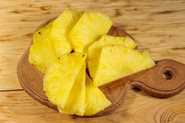 Pieces of pineapple on a cutting board on wooden table. Top view