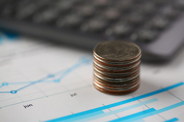 Pile of silver coins stand at financial graph papers