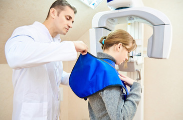 dental tomography. The human doctor puts a protective coat on the girl patient