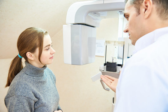 dental tomography. The doctor tells the patient what to do, both are standing next to the scanner.