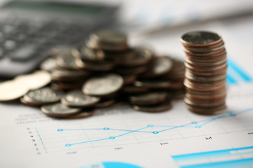 Pile of silver coins stand at financial graph papers