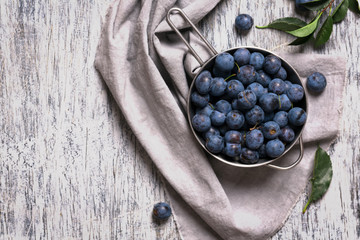 Blue blackthorn berries in metallic bowl on a table