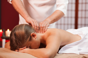 Professional spa masseur massaging neck of a female client. Woman relaxing during full body soothing massage. Cropped shot of a spa therapist working. Resort services. Traditions, travelling concept