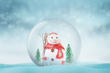 Christmas magic ball with snowman and trees on snow. Snowflakes nad bokeh in background.