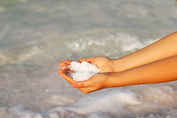 Fototapeta na wymiar girl's hands against the background of sea and salt, dead sea