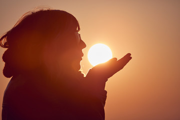 Naklejka premium Woman with praying arms enjoying the sunrise / sunset time.