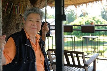 elder woman resting on terrace patio. elderly female relaxing on swing