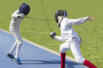Two young man fencing athletes fight on outdoor playground