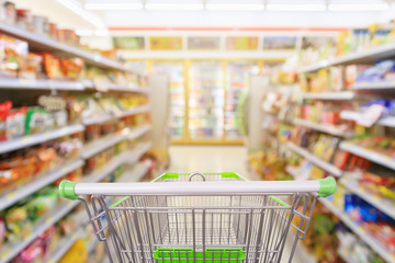 Shopping cart with Supermarket convenience store aisle shelves interior blur for background