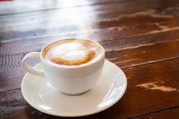 heart shape latte art in white coffee cup on wood table in cafe restaurant