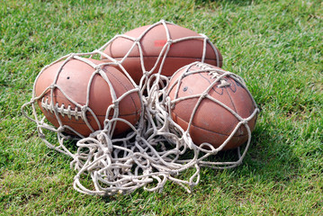 American football balls in net on field