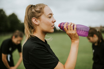 Female football player drinking from a water bottle