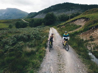Fototapeta na wymiar Couple cycling down a road in the Scottish Highlands