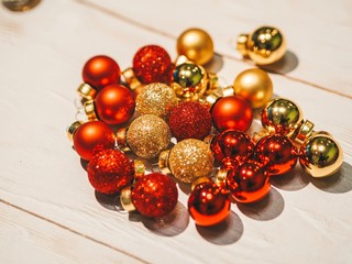 On the table are scattered small Christmas balls of gold and red flowers