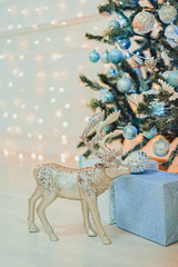 Christmas gifts and toy deer under the Christmas tree in blue.