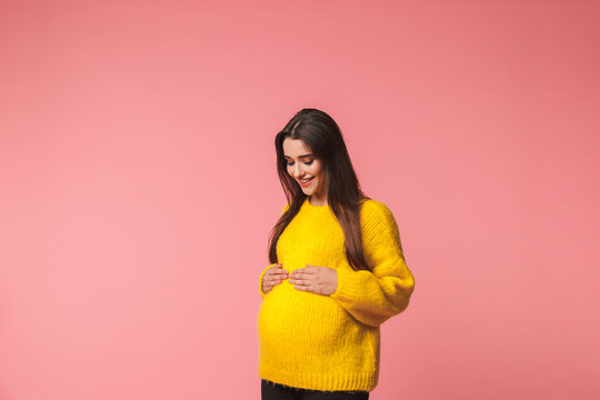 Fototapeta Beautiful young pregnant emotional woman posing isolated over pink background.