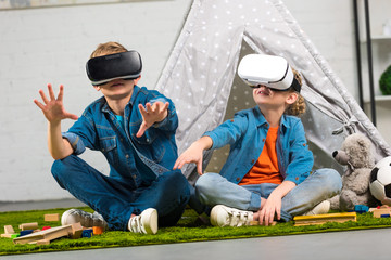 kids using virtual reality headsets and gesturing by hands near wigwam at home