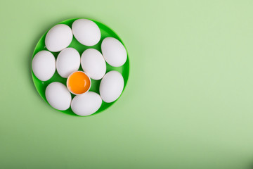 White eggs and egg yolk on the green background