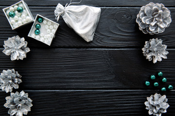 Silver cones and emerald green beads on black table. Space for text.