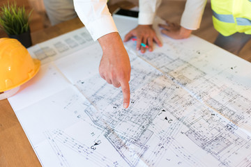 Real estate and architects concept. Architect pointing finger on blueprint on the desk and discussing building plan of a new house. Moving house concept.