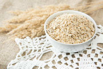 Oatmeal in white bowl with spikes on textile background. Healthy eating