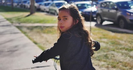 Little girl on bicycle looking back at camera, smiles