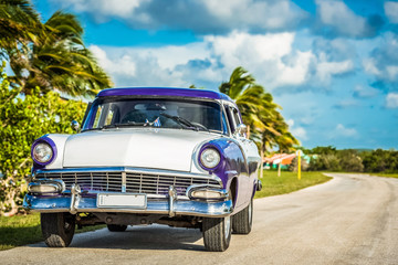 Obraz na płótnie Canvas Blau weißer amerikanischer Oldtimer parkt auf der Strasse auf dem Malecon nahe des Strandes in Havana Cuba - Serie Cuba Reportage