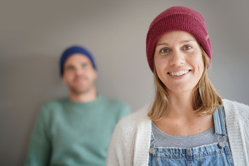  Portrait of smiling woman wearing wooly hat with partner in background