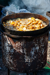 Roasted potatoes cooking in cast-iron frying pan outdoors