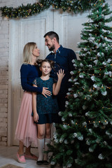 Christmas photo of happy family with gift boxes on background of decorated Christmas tree. Family celebrates New year