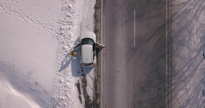 Aerial drone footage of white car parked by the road and couple coming out from car.