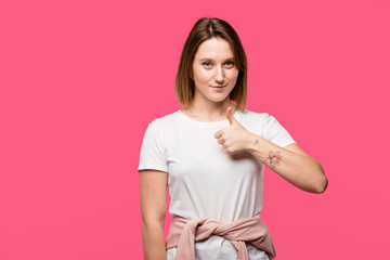 cheerful stylish girl showing thumb up gesture isolated on pink