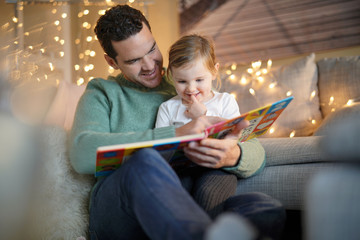  Father and daughter reading a story at home - obrazy, fototapety, plakaty