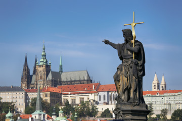 Obraz premium Prague, Czech Republic, sculpture on the Charles Bridge against the background of the blue sky and Prague Castle