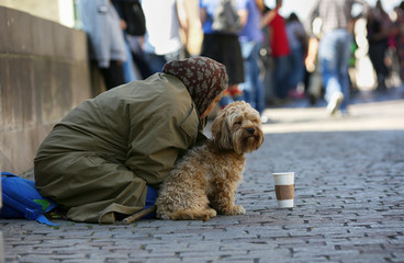 Prague, Czech Republic, September 17, 2018. Old beggar woman with dog begging on the Charles Bridge