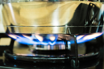 Close up of stainless steel saucepan on gas stove burner.