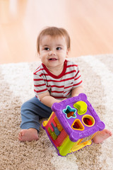 Toddler sitting on carpet and playing with a shape sorter