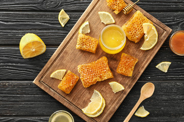 Jar with sweet honey and pieces of fresh combs on wooden board