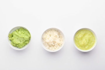 Bowls with healthy baby food on white background