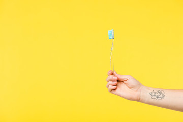 cropped shot of person holding toothbrush isolated on yellow