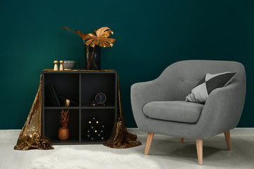 Stylish interior of room with comfortable armchair and golden decor