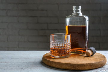 Bottle and glass of whiskey on light table